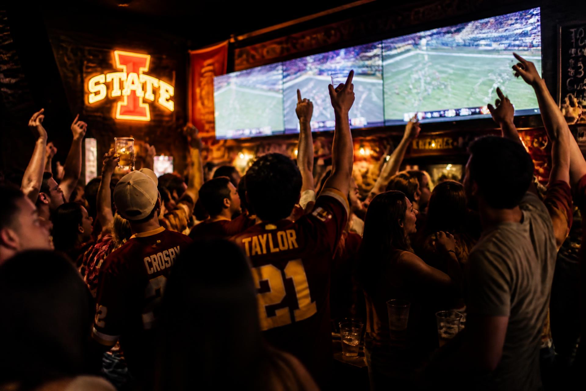 Students cheering at a packed sports bar